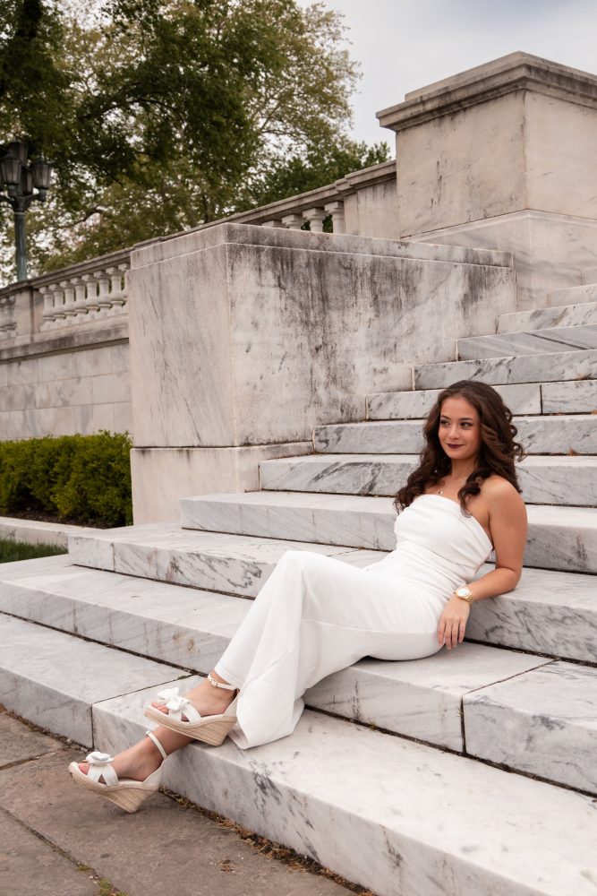 Young woman in an elegant white dress posing in a park at sunset during a graduation photoshoot in Cleveland, Ohio, with soft golden light 