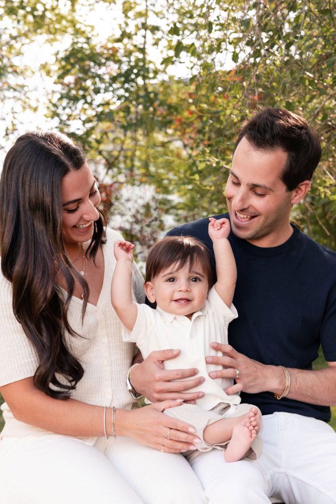 Outdoor family portrait of a mother, father, and their one-year-old son smiling together during a first birthday photography session in Cleveland, Ohio.