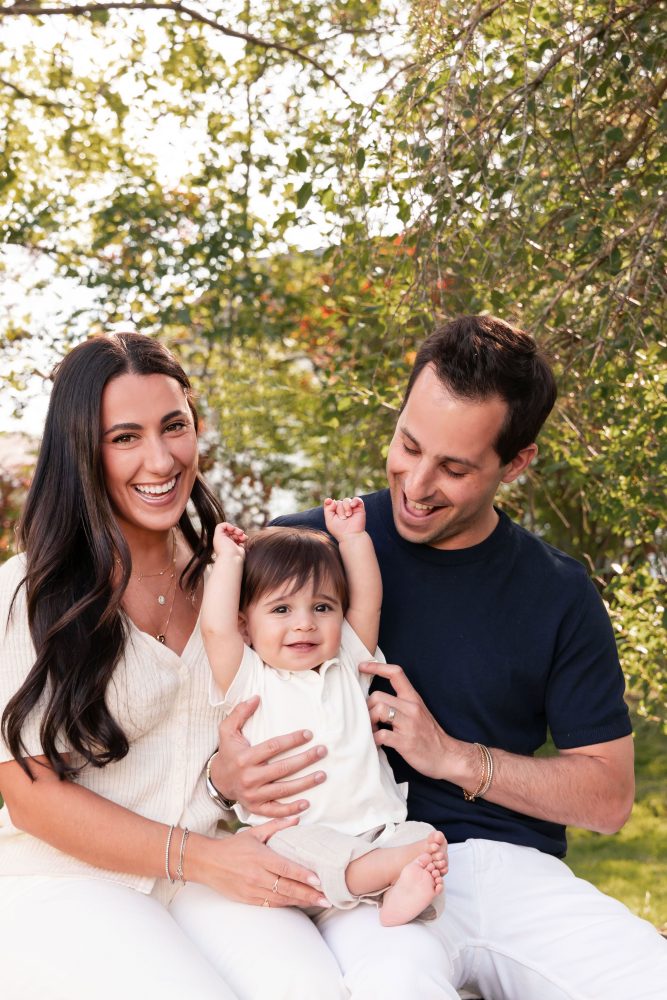 Outdoor family portrait of a mother, father, and their one-year-old son smiling together during a first birthday photography session in Cleveland, Ohio.