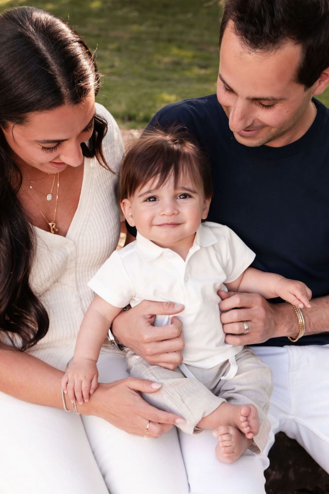 Outdoor family portrait of a mother, father, and their one-year-old son smiling together during a first birthday photography session in Cleveland, Ohio.