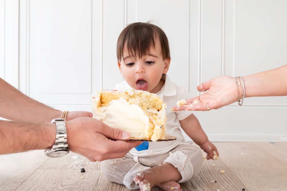 Baby boy with frosting on his face smiling during a simple white cake smash photography session by Allison Liffman Photography.