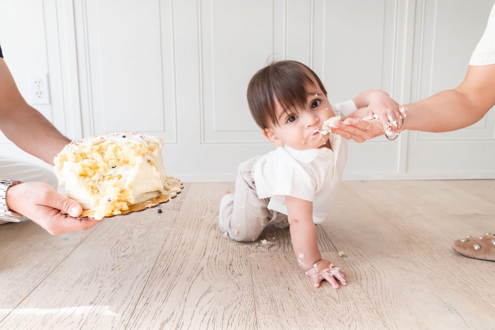 Classic first birthday cake smash featuring a one-year-old boy and vanilla birthday cake in a bright Cleveland photography studio.