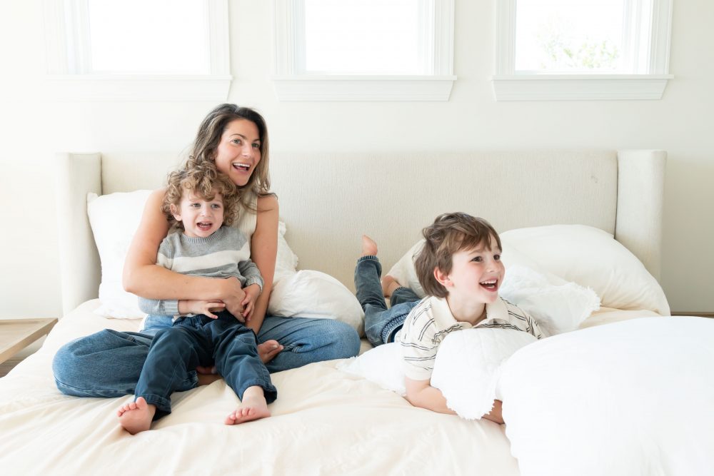 Mother laughing with her two young sons during an in-home lifestyle family photography session by a Cleveland family photographer.