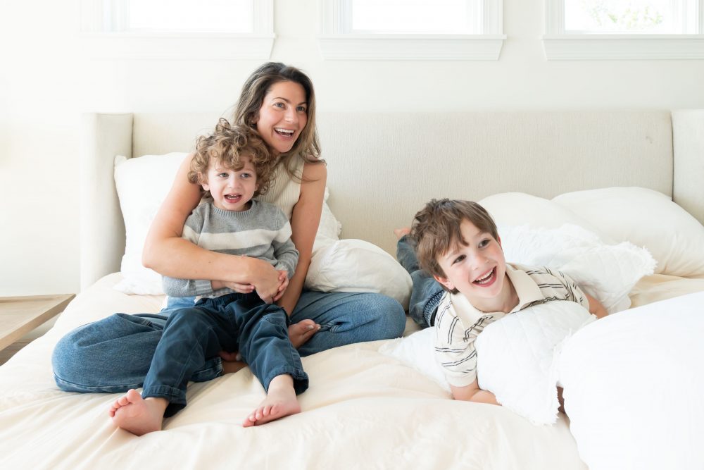 Mother laughing with her two young sons during an in-home lifestyle family photography session by a Cleveland family photographer.