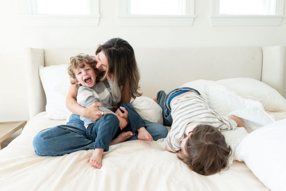 Mother laughing with her two young sons during an in-home lifestyle family photography session by a Cleveland family photographer.