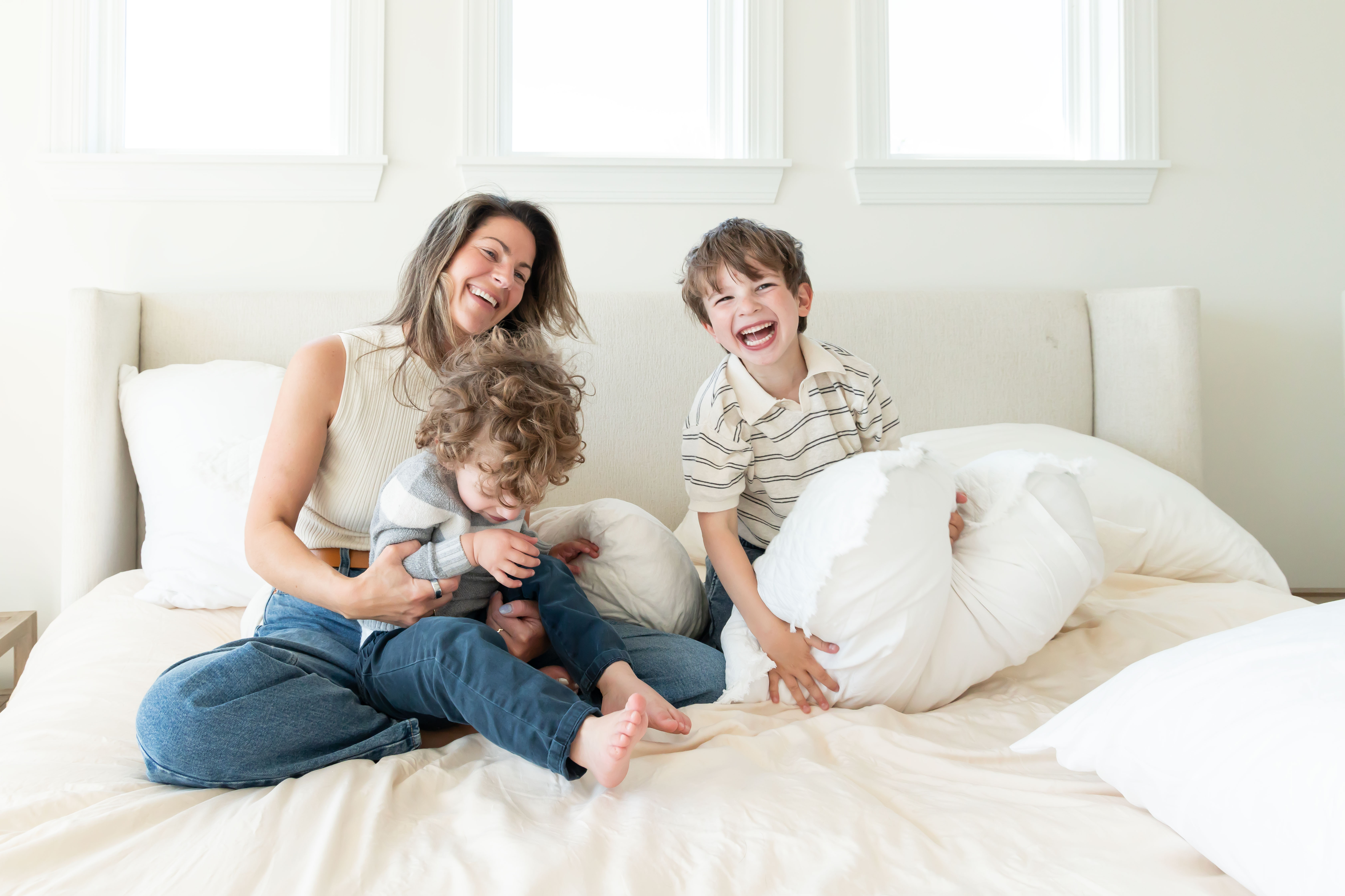 Mother laughing with her two young sons during an in-home lifestyle family photography session by a Cleveland family photographer.