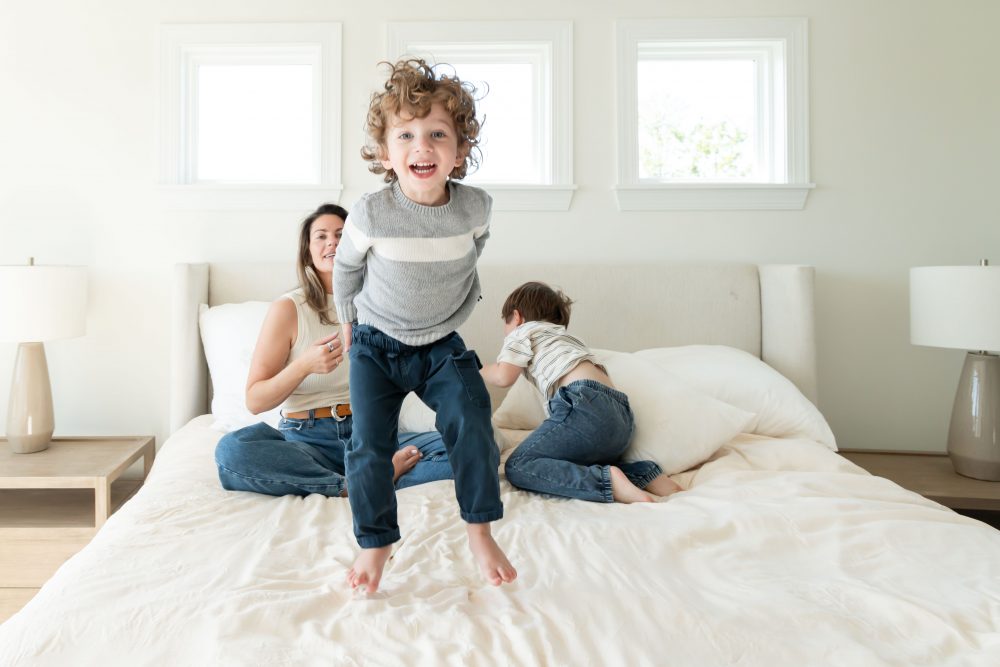 Mother laughing with her two young sons during an in-home lifestyle family photography session by a Cleveland family photographer.