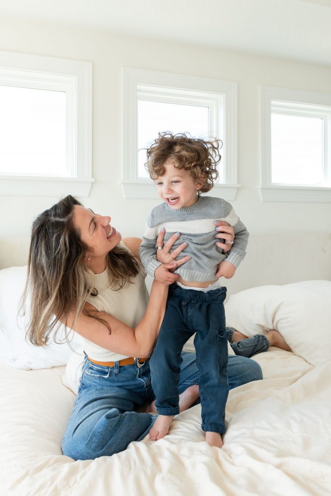 Mother laughing with her two young sons during an in-home lifestyle family photography session by a Cleveland family photographer.
