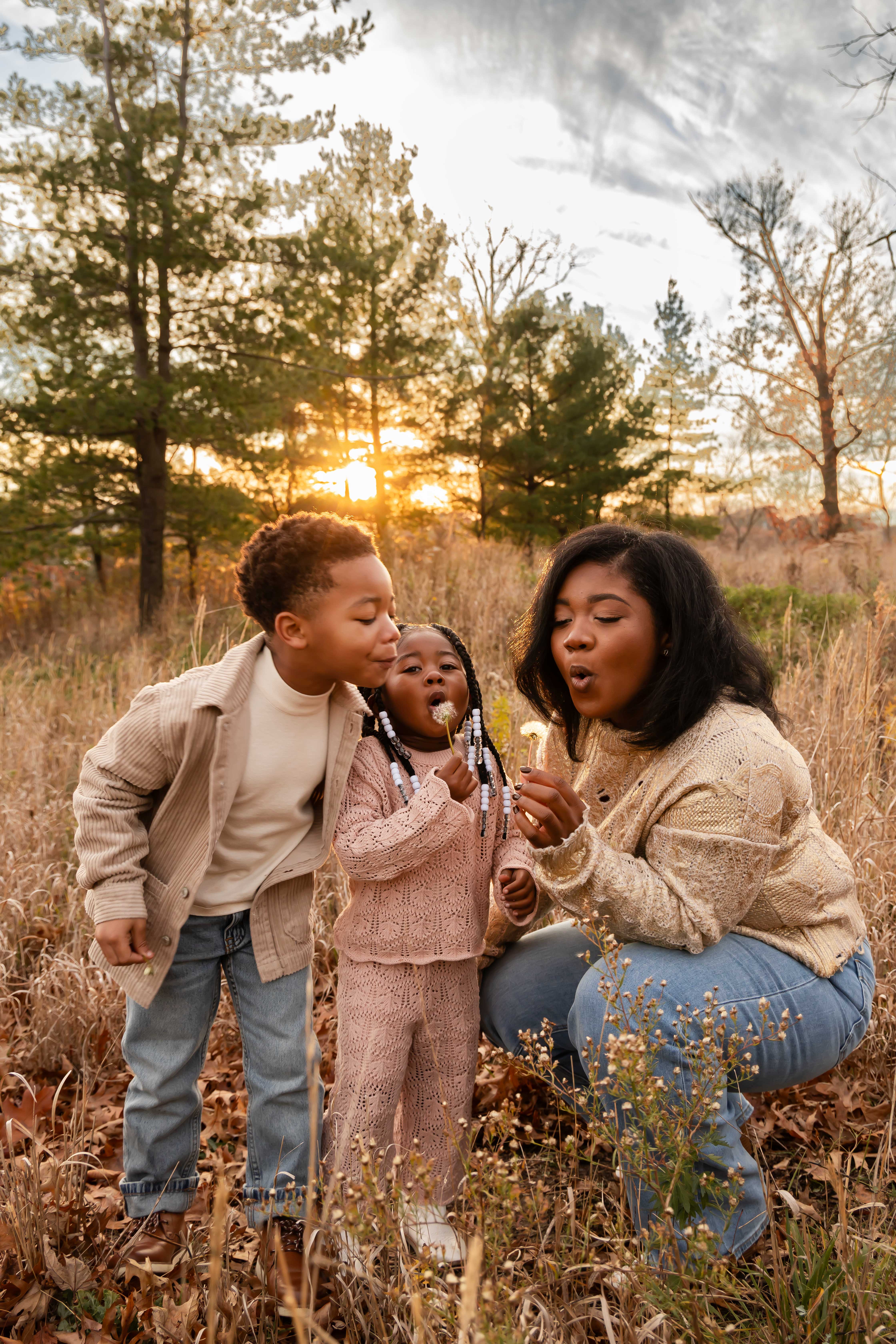 Mother with her son and daughter blowing daffodils during a Cleveland, Ohio sunset photography session