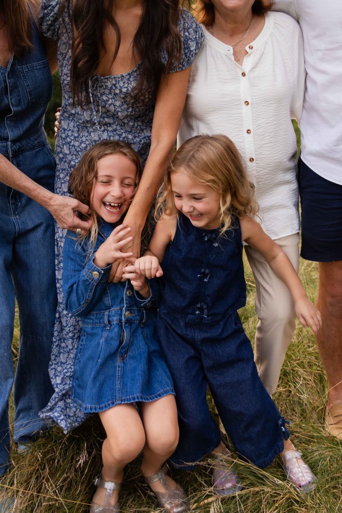 Two young sisters cuddling together during an extended family photography session