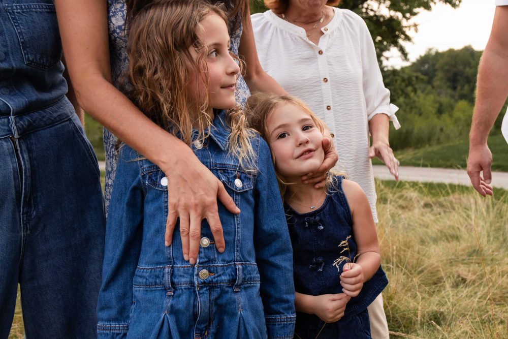 Two young sisters cuddling together during an extended family photography session