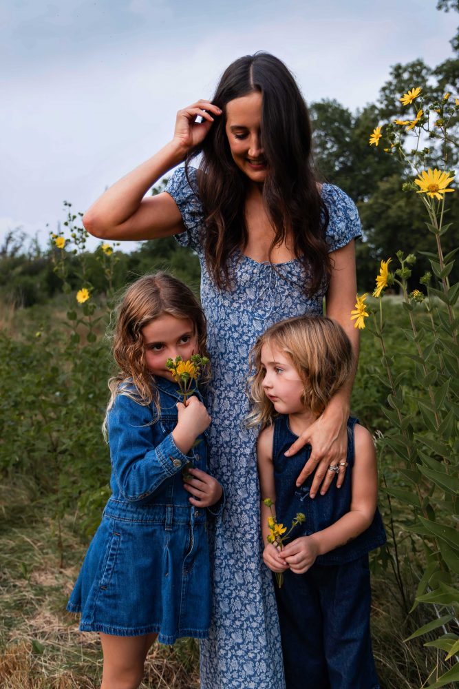 Mother and daughters sharing a tender moment surrounded by wildflowers