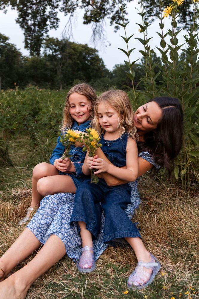 Mother and daughters sharing a tender moment surrounded by wildflowers