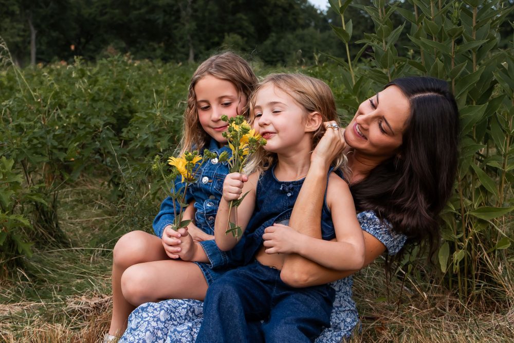 Mother and daughters sharing a tender moment surrounded by wildflowers