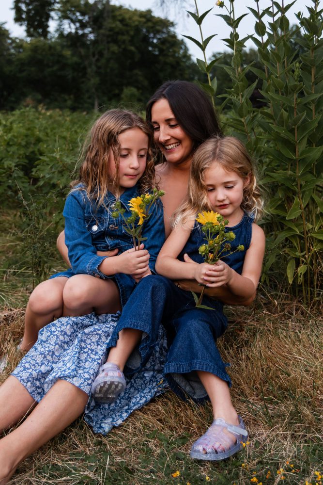 Mother and daughters sharing a tender moment surrounded by wildflowers