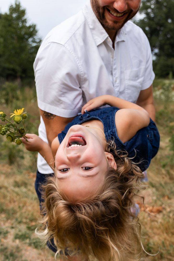 dad playing with his daughters in a field during a Cleveland sunset family photoshoot