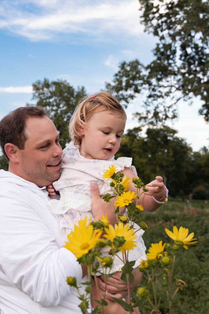 Father holding his young daughter surrounded by yellow wildflowers during a Cleveland family photography session