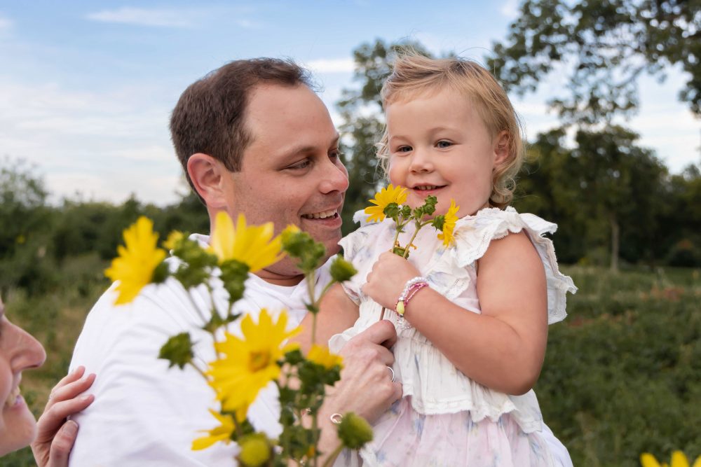 Father holding his young daughter surrounded by yellow wildflowers during a Cleveland family photography session