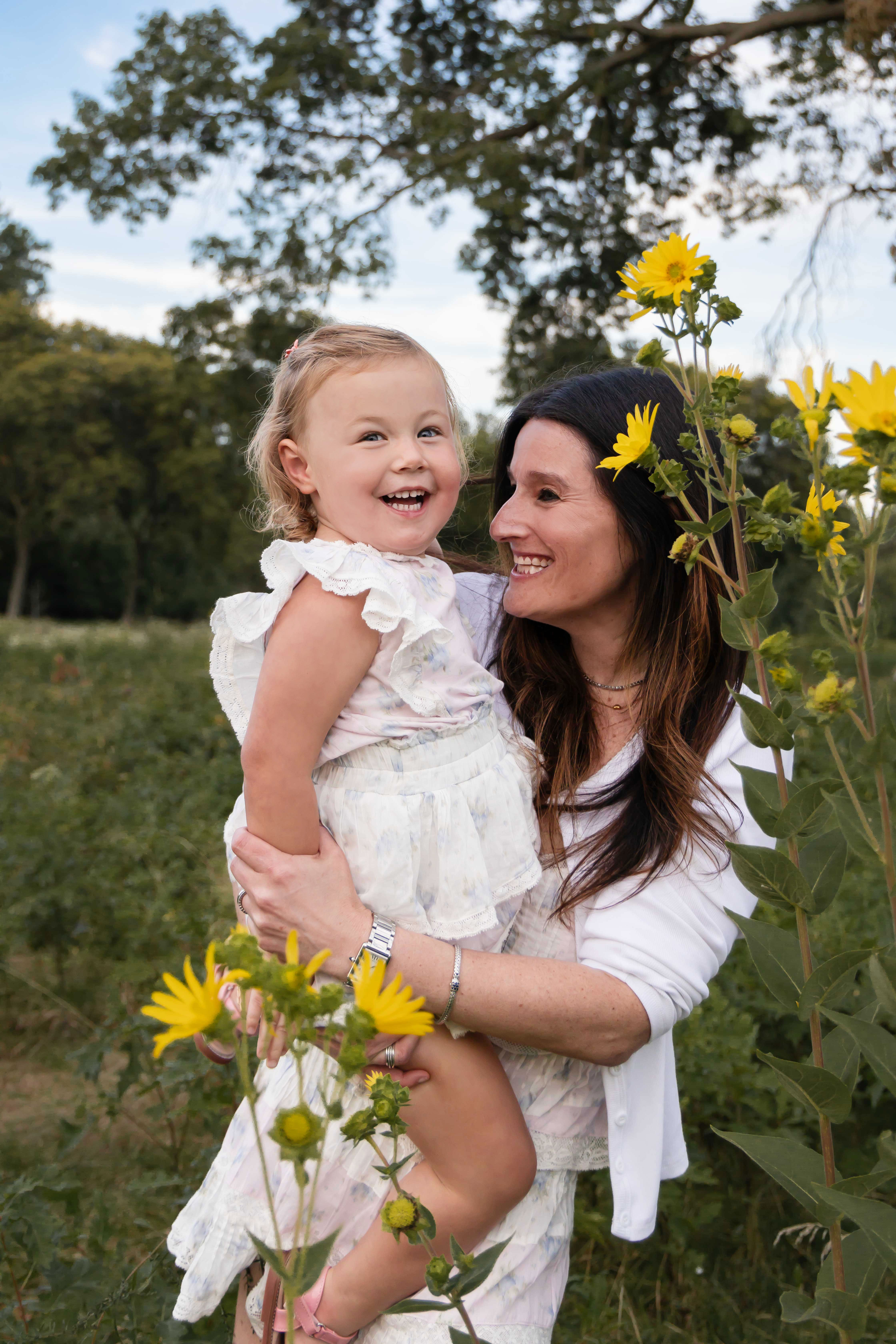 Mother holding her young daughter surrounded by yellow wildflowers during a Cleveland family photography session