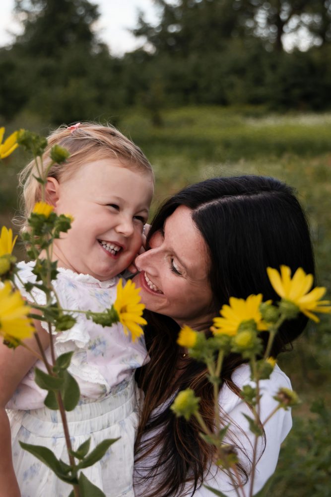 Mother holding her young daughter surrounded by yellow wildflowers during a Cleveland family photography session