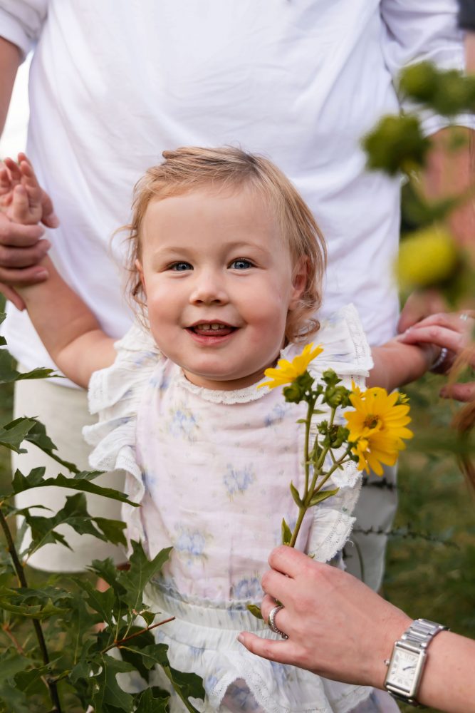 Young girl smiling while holding a yellow wildflower during a Cleveland family photography session