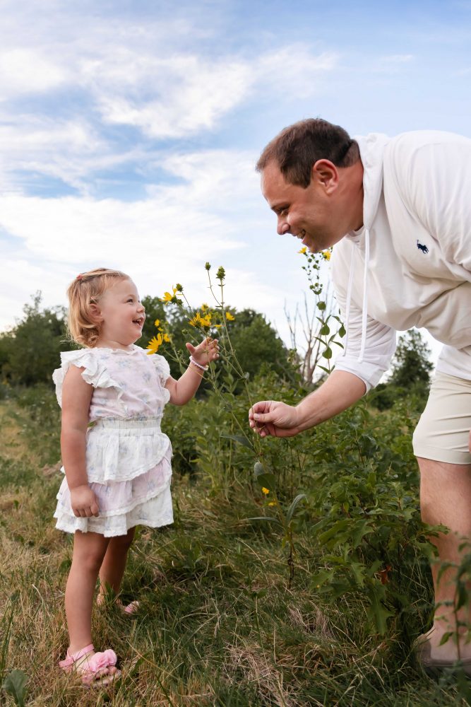 Father handing his daughter wildflowers in the Cleveland park during sunset 