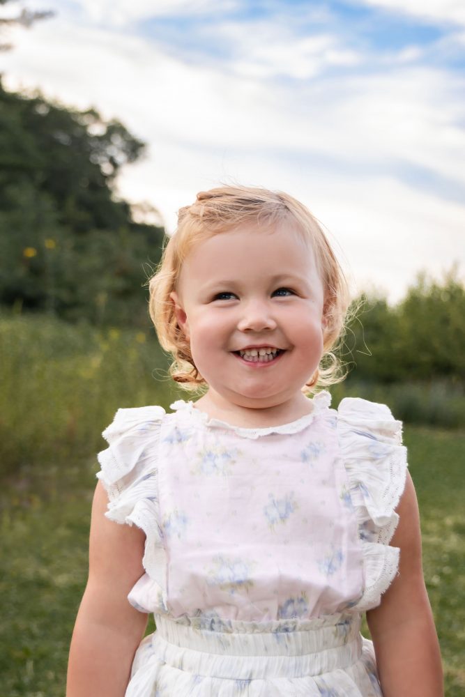 Young child smiling at the camera while holding flowers during a Cleveland family photo session