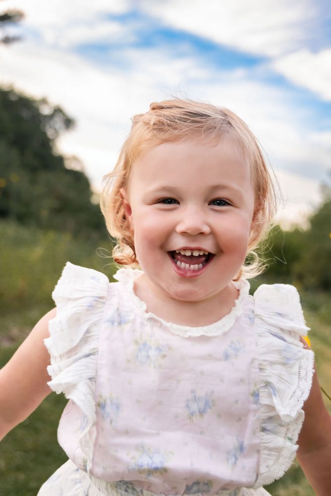 Young child smiling at the camera while holding flowers during a Cleveland family photo session