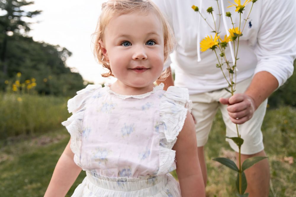 Cleveland family photographer captures a young daughter smiling among yellow wildflowers