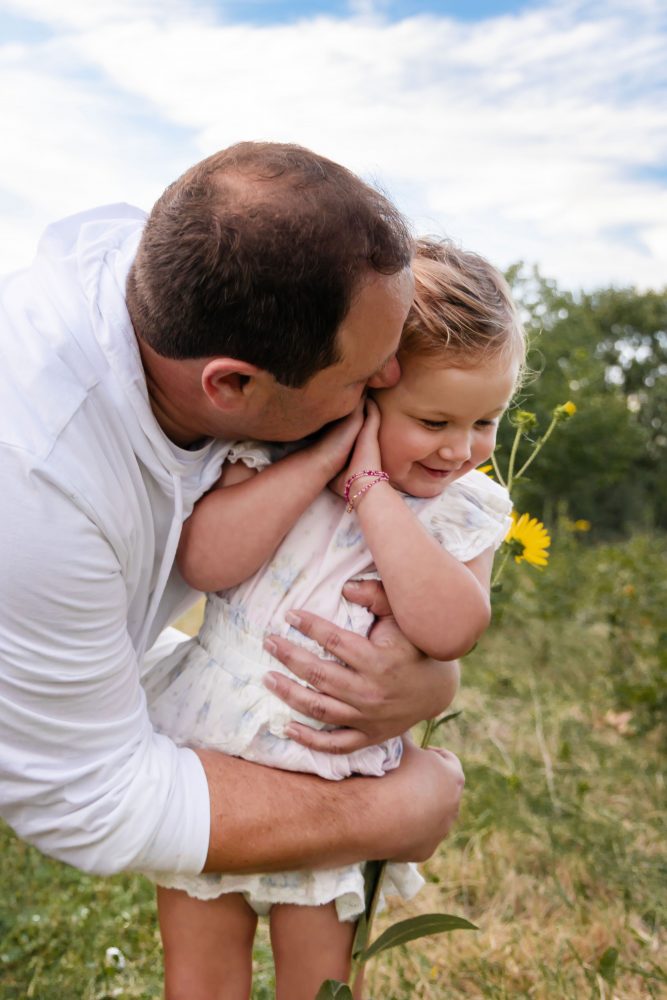 Father holding and cuddling his daughter during an outdoor sunset photography session in Cleveland, Ohio