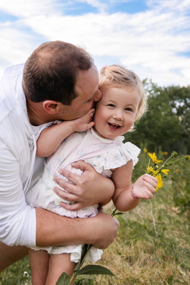 Father holding and cuddling his daughter during an outdoor sunset photography session in Cleveland, Ohio