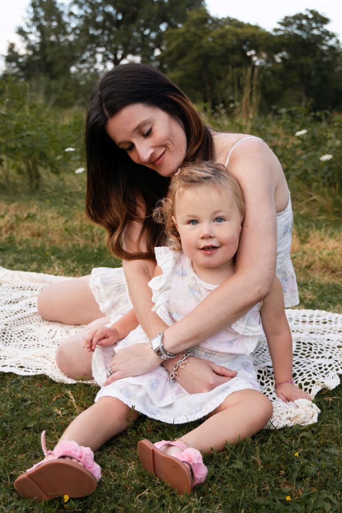 Mother cuddling her daughter while sitting together on a blanket during a Cleveland family photography session