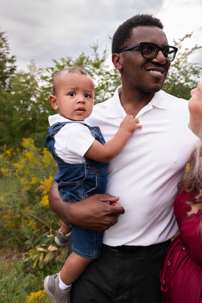 Dad holding his baby while standing with his wife and young son during a Cleveland family photography session.