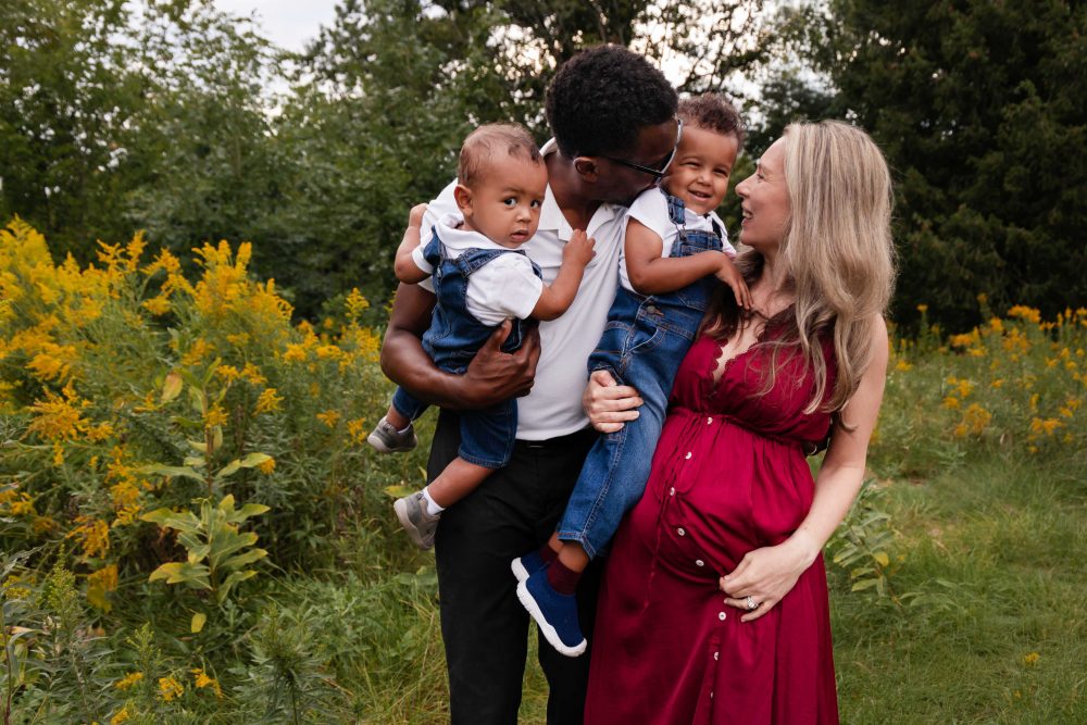 Pregnant woman in a burgundy dress standing among golden wildflowers during a Cleveland maternity photography session.