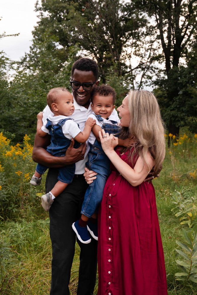 Pregnant woman in a burgundy dress standing among golden wildflowers during a Cleveland maternity photography session.