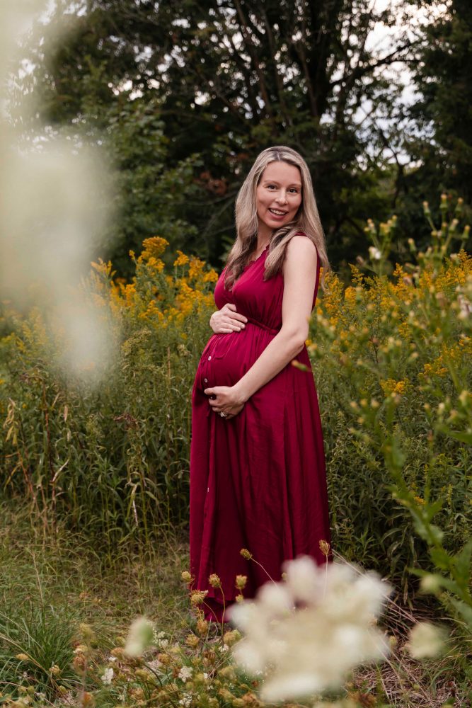 Pregnant woman smiling while standing in a wildflower field during her Cleveland maternity photo session.