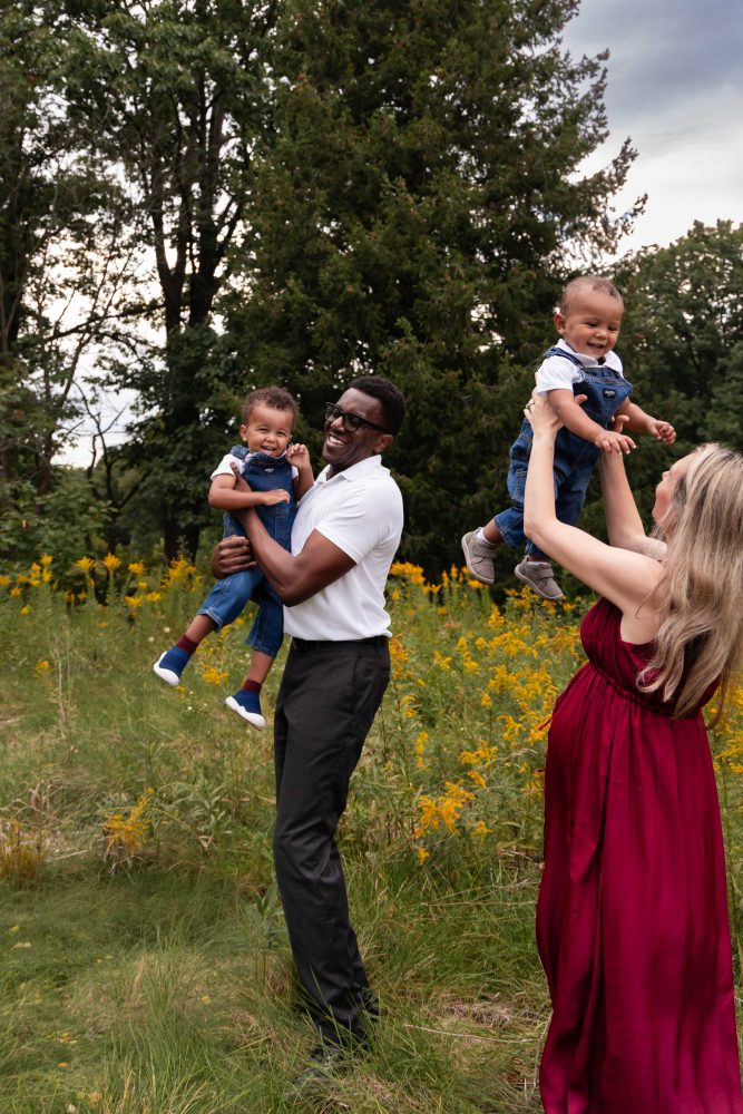 Family of four laughing together during an outdoor Cleveland family photography session in a wildflower field.
