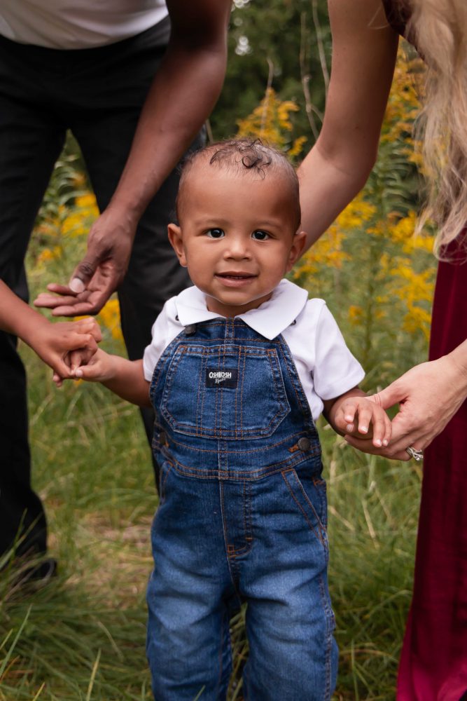 Young family enjoying a playful moment together during an outdoor family photography session surrounded by wildflowers.