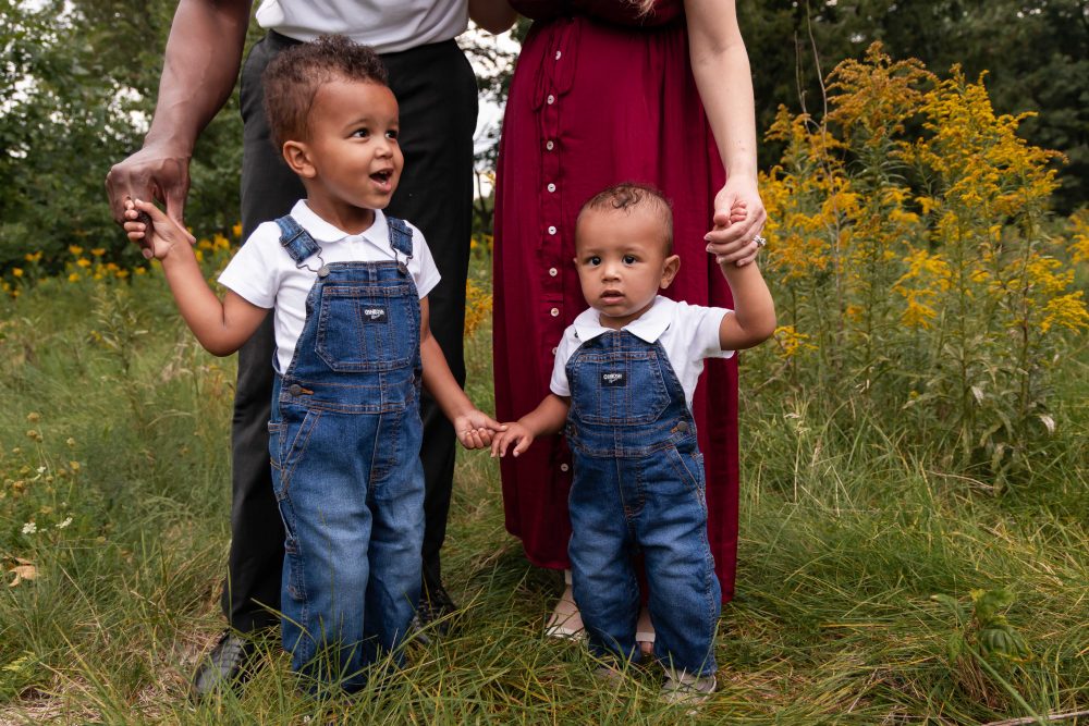Warm, candid family photograph of parents and their two sons in a wildflower field by Allison Liffman Photography.
