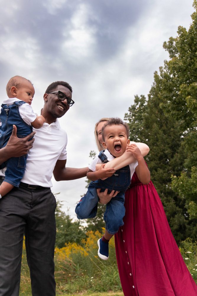 Warm, candid family photograph of parents and their two sons in a wildflower field by Allison Liffman Photography.