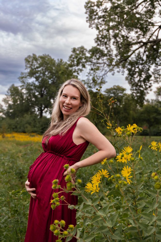 Pregnant woman smiling while standing in a wildflower field during her Cleveland maternity photo session.
