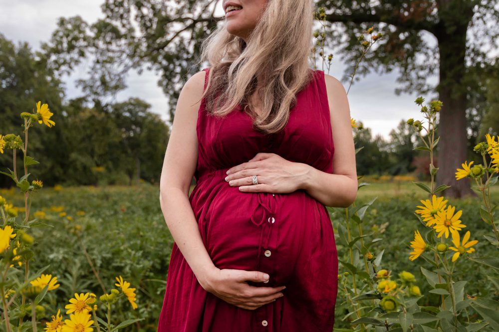Natural maternity portrait of an expectant mother surrounded by yellow flowers and greenery in Cleveland.