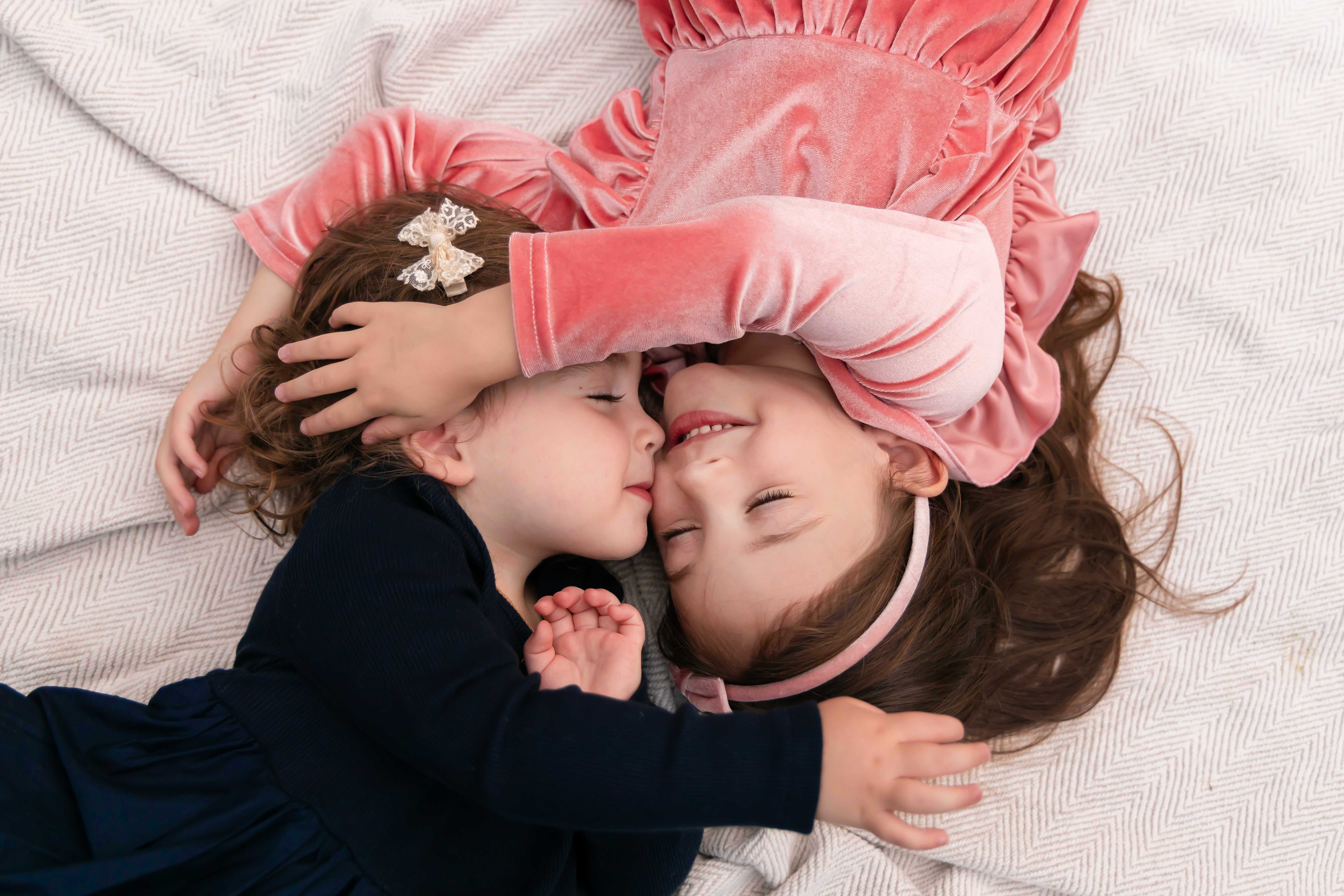 Sisters embrace laying on a blanket at an outdoor sunset family photoshoot in Cleveland, Ohio