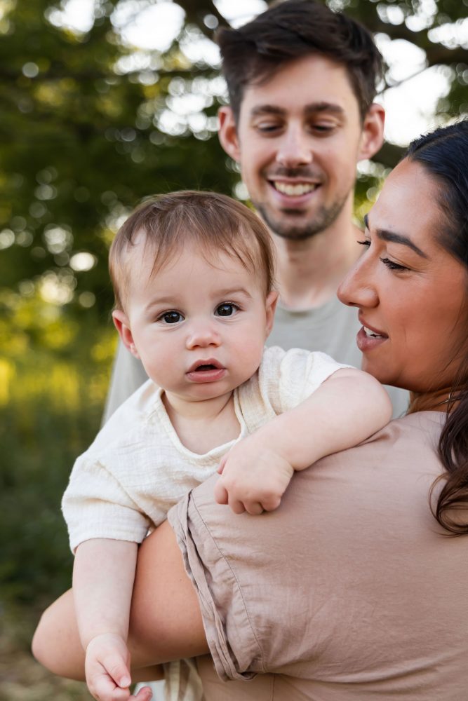 A smiling baby resting on his mother's shoulder during a warm, natural family photography session in Cleveland, Ohio.