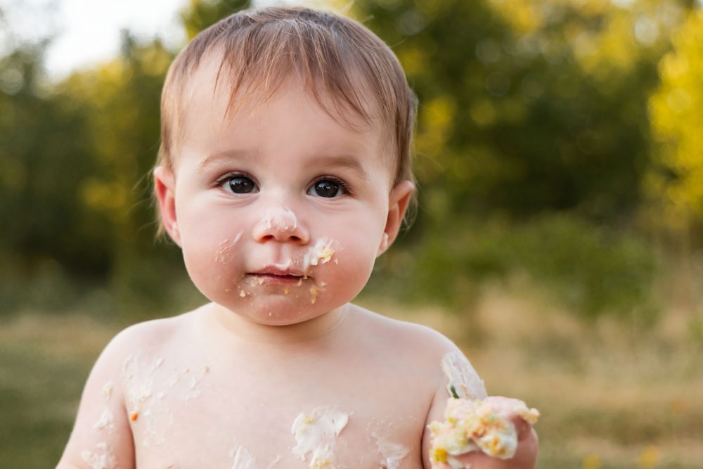 Cleveland baby photographer Allison Liffman captures a playful cake smash moment with a smiling baby covered in frosting.