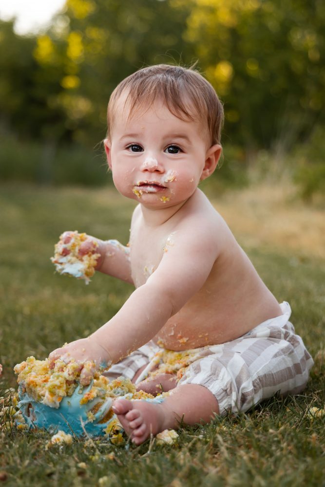 Cleveland baby photographer Allison Liffman captures a playful cake smash moment with a smiling baby covered in frosting.