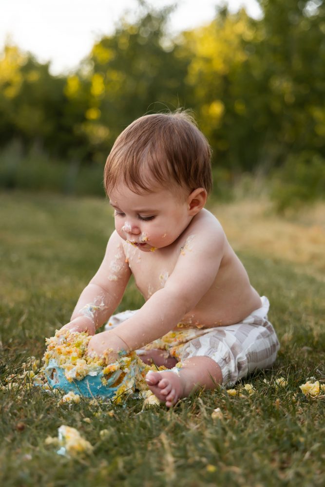 Cleveland cake smash photographer captures a laughing baby boy covered in birthday cake frosting during his first birthday session.