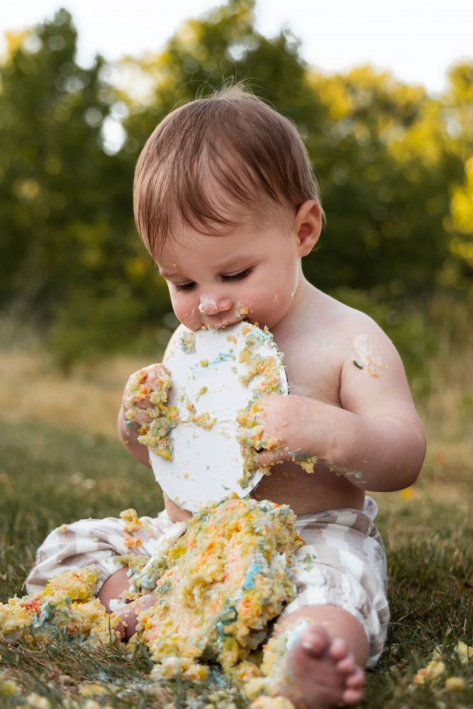 Cleveland cake smash photographer captures a laughing baby boy covered in birthday cake frosting during his first birthday session.