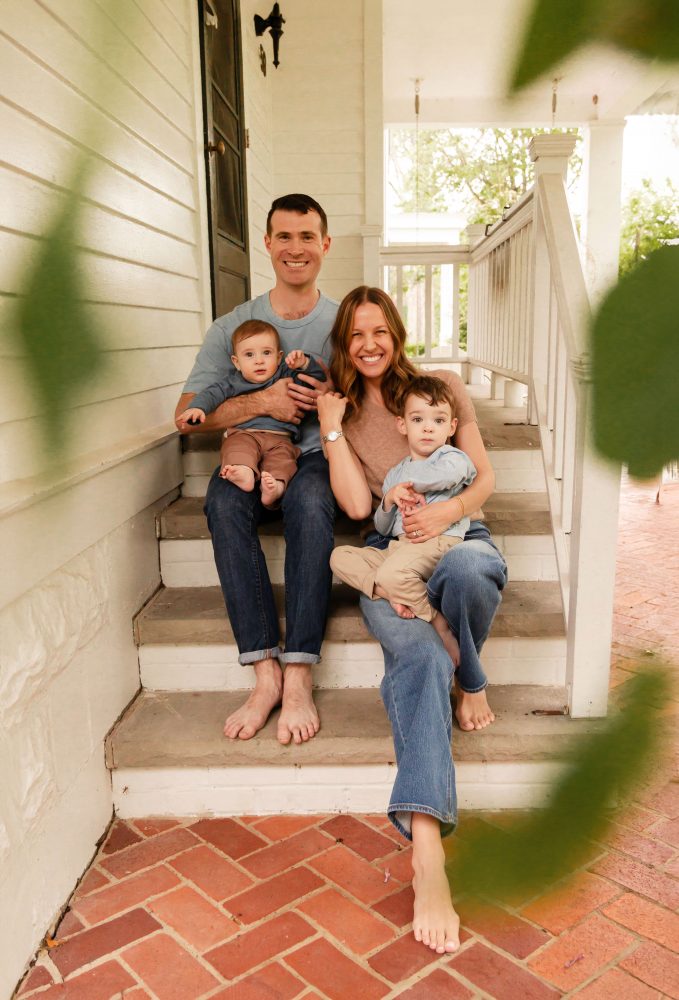 Parents holding their two young boys on the steps of a white house during a Cleveland family photo session.