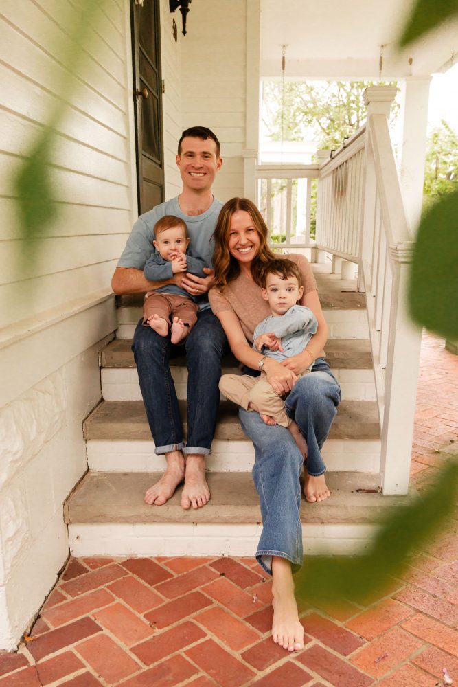 Parents holding their two young boys on the steps of a white house during a Cleveland family photo session.